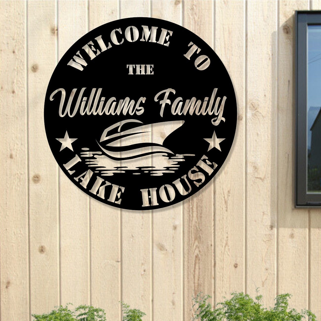 Round metal sign with 'Welcome to the Williams Family Lake House' text and boat graphic on a wooden wall.