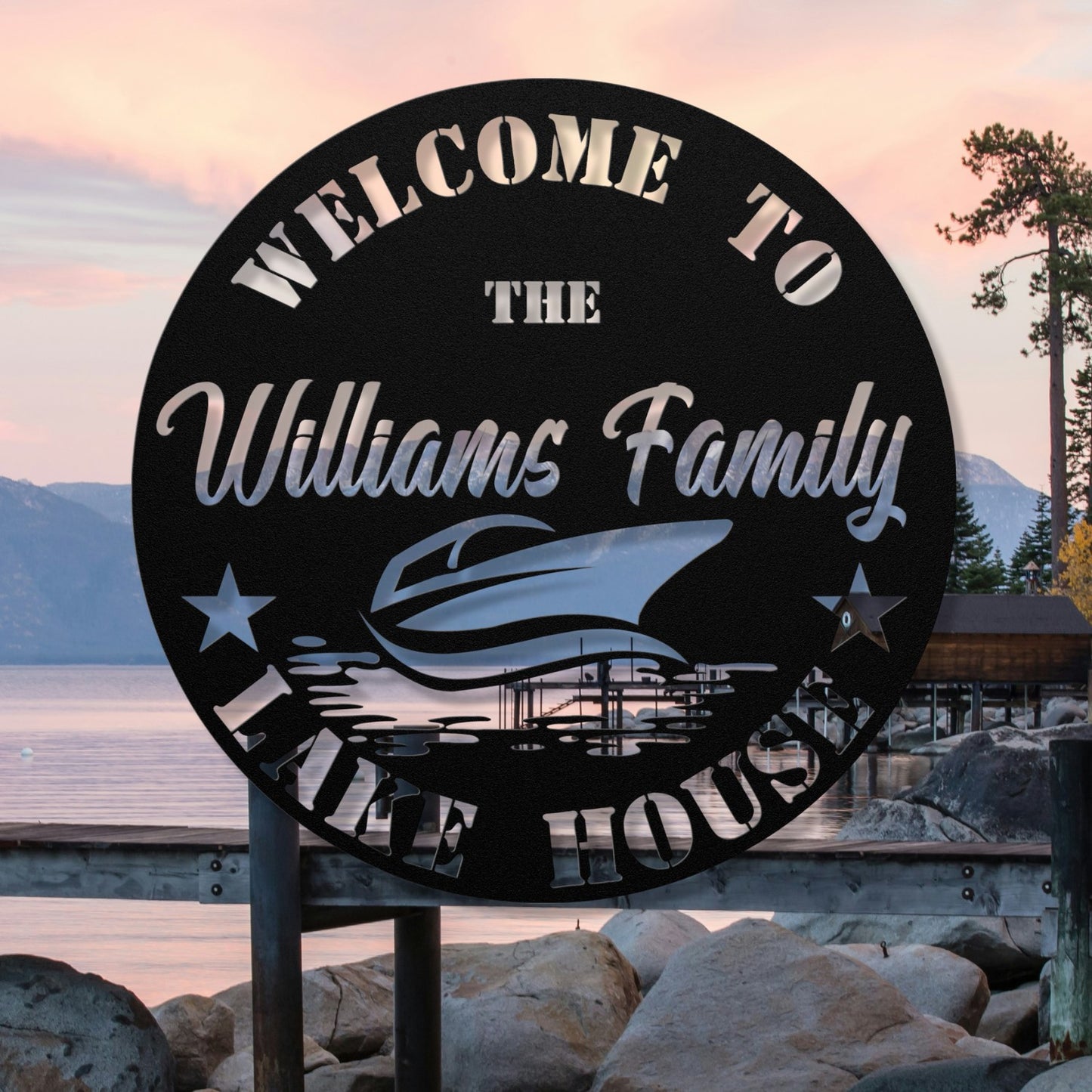 Round metal sign welcoming visitors to 'The Williams Family Lake House' with a scenic background.