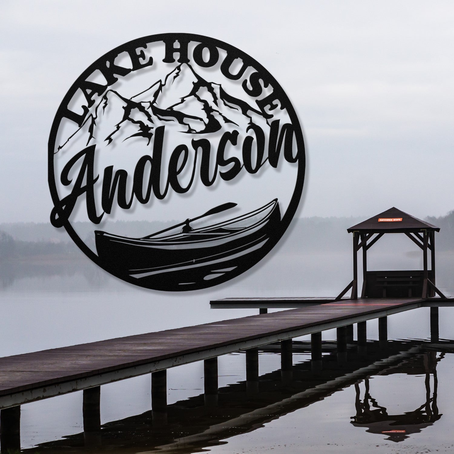 Decorative metal wall art with 'Lake House Anderson' text, mountains, and a canoe design on a white wall.